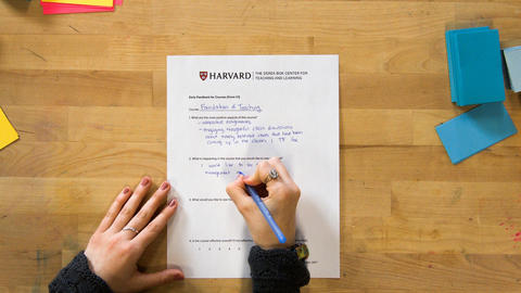 Overhead view of hands writing feedback on an evaluation form.