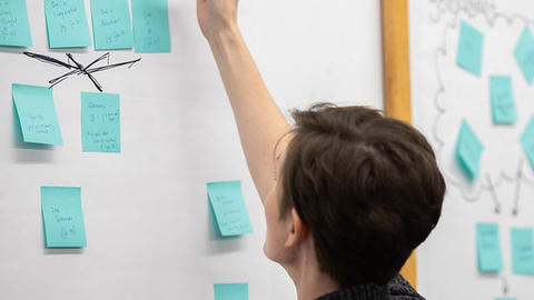 person writing on board with sticky notes