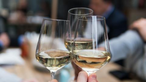 three glasses of white wine touching in "cheers"