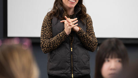 A pedagogy fellow stands in front of a group of her peers answering a question.