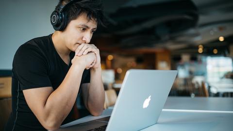 man wearing headphones looking at laptop