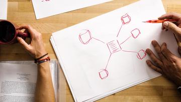 Top down image of hands drawing a diagram on a piece of paper.