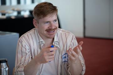 student in striped shirt smiling at table