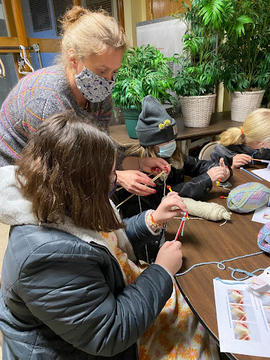 Rebecca Brown teaching a girl scout how to knit.