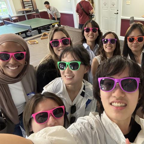 A group of ISI participants pose for a selfie wearing brightly colored sunglasses.