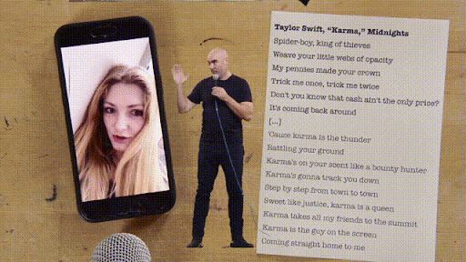 Person on a green screen stage holding a microphone overlaid on a wood table displaying Taylor Swift song lyrics and an iPhone showing a TikTok clip.