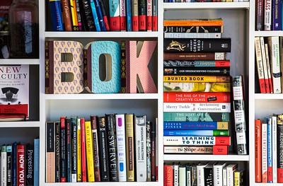 white bookshelves with stacks of books and letters spelling out 