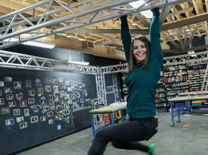 Lauren hangs acrobatically from scaffolding.