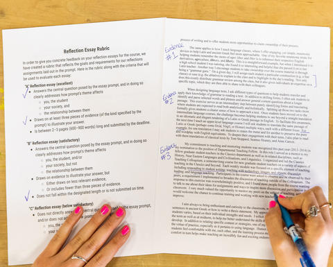 An overhead image of hands writing on papers on a wooden table.